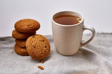 Beyaz porselen kupa çay ve tatlı kurabiye beyaz arka plan, üstten görünüm, seçici odak saf peçete üzerinde