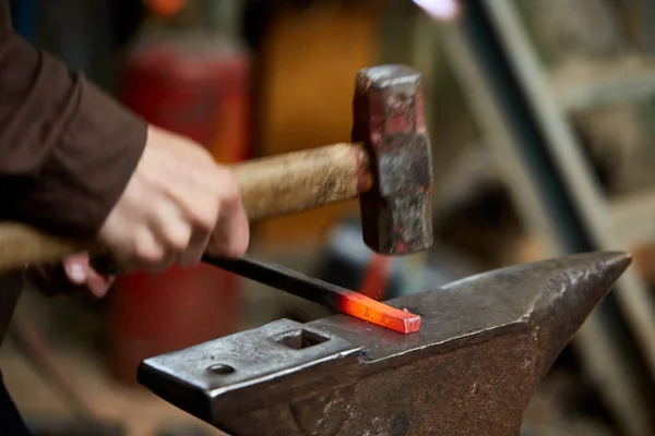 Treatment of molten metal on blurred background, close-up.