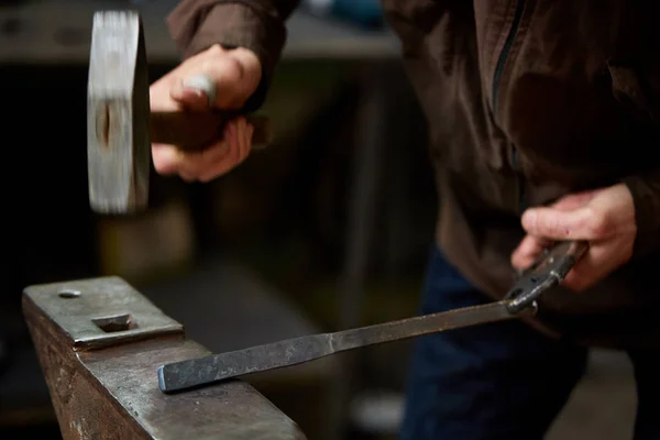 Close-up van een smeden handen manipuleren van een metalen stuk boven zijn smederij, selectieve aandacht. — Stockfoto