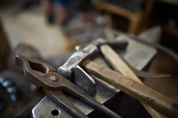 Close-up van een smeden handen manipuleren van een metalen stuk boven zijn smederij, selectieve aandacht. — Stockfoto