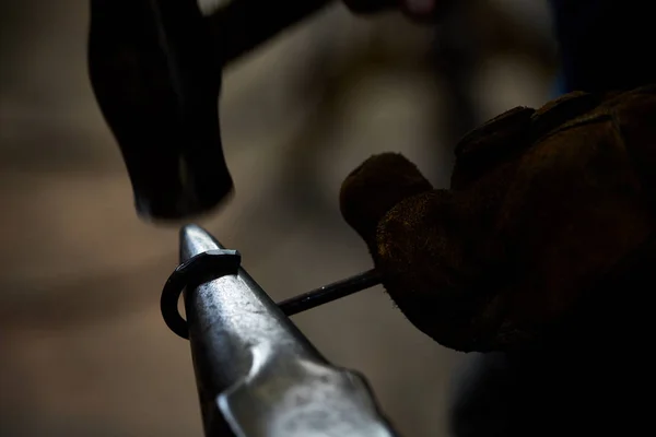 Close-up van een smeden handen manipuleren van een metalen stuk boven zijn smederij, selectieve aandacht. — Stockfoto