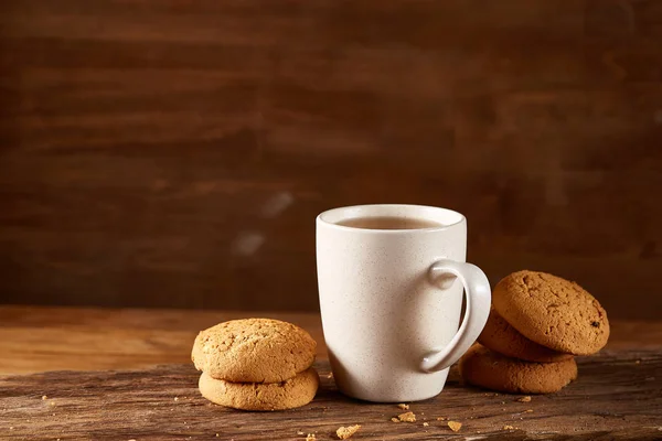 Taza blanca de té y galletas en un registro sobre fondo de madera estilo país, primer plano, enfoque selectivo — Foto de Stock