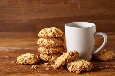 Beyaz porselen kupa çay ve tatlı kurabiye ahşap arka plan, üstten görünüm, seçici odak