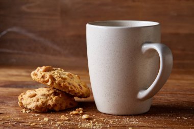 Beyaz porselen kupa çay ve tatlı kurabiye ahşap arka plan, üstten görünüm, seçici odak