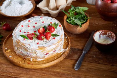 Çilekli tart ahşap arka plan üzerinde düz yatıyordu organik maddeler tarafından çevrili ekşi krem şanti ile kaplı.