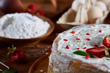 Çilekli tart ahşap arka plan üzerinde düz yatıyordu organik maddeler tarafından çevrili ekşi krem şanti ile kaplı.