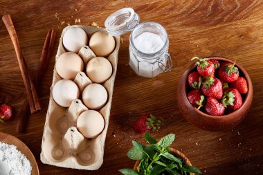 Çilekli tart ahşap arka plan üzerinde düz yatıyordu organik maddeler tarafından çevrili ekşi krem şanti ile kaplı.