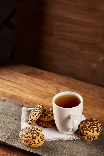 Chávena branca de chá e biscoitos em um log sobre fundo de madeira estilo country, close-up, foco seletivo — Fotografia de Stock