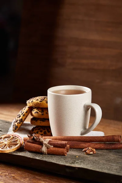 Taza blanca de té y galletas en un registro sobre fondo de madera estilo país, primer plano, enfoque selectivo —  Fotos de Stock