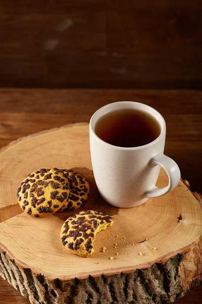 Chávena branca de chá e biscoitos em um log sobre fundo de madeira estilo country, close-up, foco seletivo — Fotografia de Stock