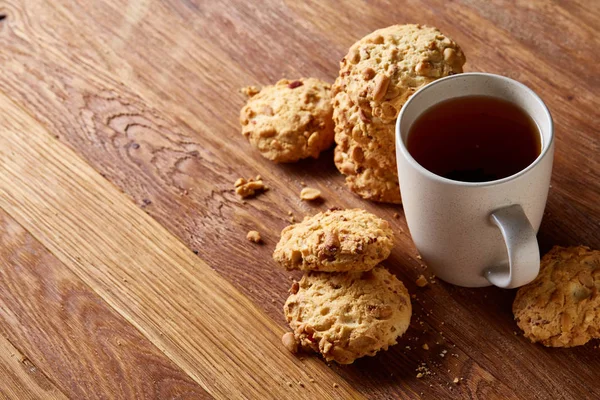 Beyaz porselen kupa çay ve tatlı kurabiye ahşap arka plan, üstten görünüm, seçici odak