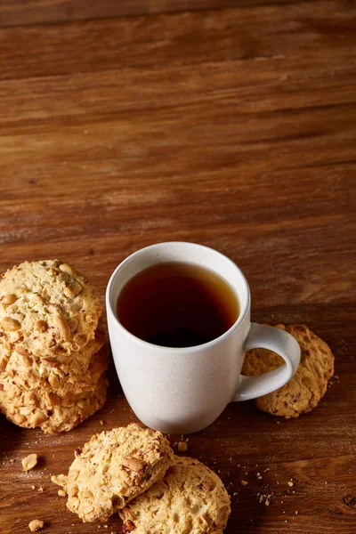 Beyaz porselen kupa çay ve tatlı kurabiye ahşap arka plan, üstten görünüm, seçici odak