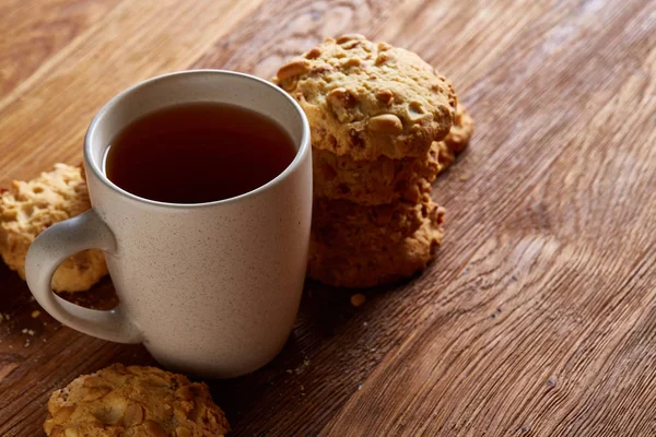 White porcelain mug of tea and sweet cookies on wooden background, top view, selective focus — Stock Photo, Image