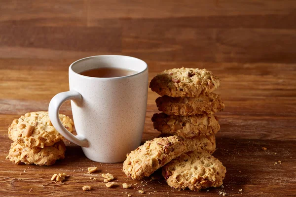 Beyaz porselen kupa çay ve tatlı kurabiye ahşap arka plan, üstten görünüm, seçici odak