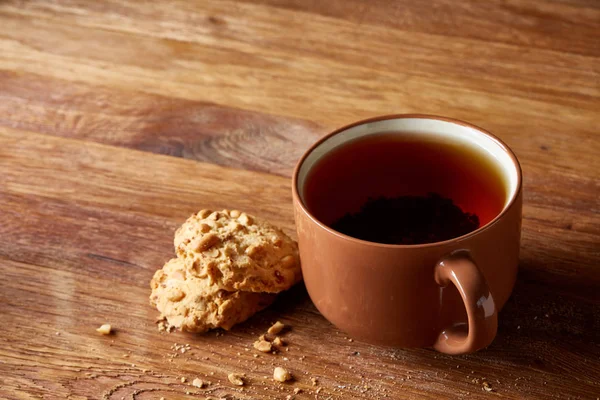 Porzellantasse Tee und süße Kekse auf Holzgrund, Draufsicht, selektiver Fokus — Stockfoto