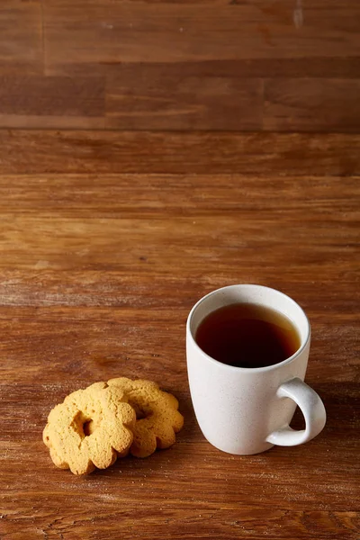 Beyaz porselen kupa çay ve tatlı kurabiye ahşap arka plan, üstten görünüm, seçici odak