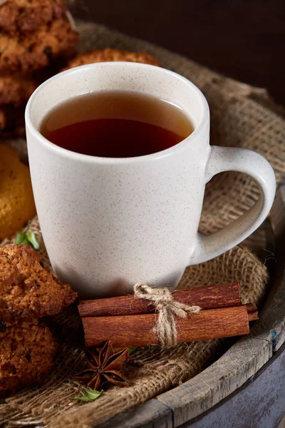 Concepto tradicional de té de Navidad con una taza de té caliente, galletas y decoraciones sobre un fondo de madera, enfoque selectivo —  Fotos de Stock