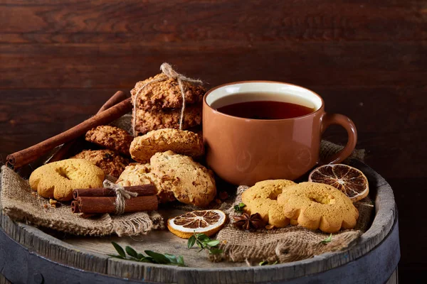 Traditional Christmas tea concept with a cup of hot tea, cookies and decorations on a wooden background, selective focus — Stock Photo, Image