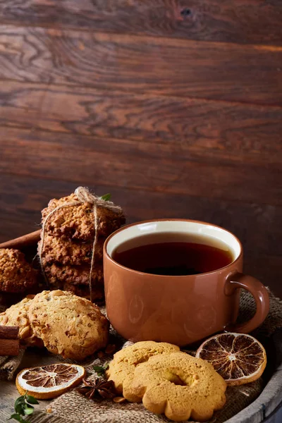 Traditionelles Konzept des Weihnachtstees mit einer Tasse heißem Tee, Plätzchen und Dekorationen auf Holzgrund, selektiver Fokus — Stockfoto