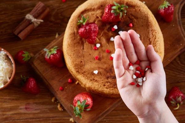 Kızlar el üst kısmındaki lezzetli çilekli pasta dekorasyon kapat, seçici odak, kapat.