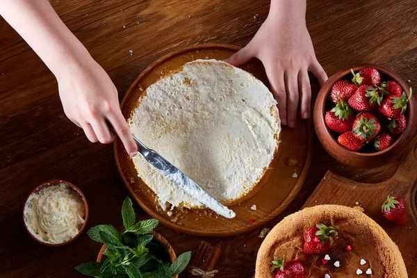 Kızlar el krem lezzetli çilekli pasta üstüne ekleme kapat, seçici odak, kapat.