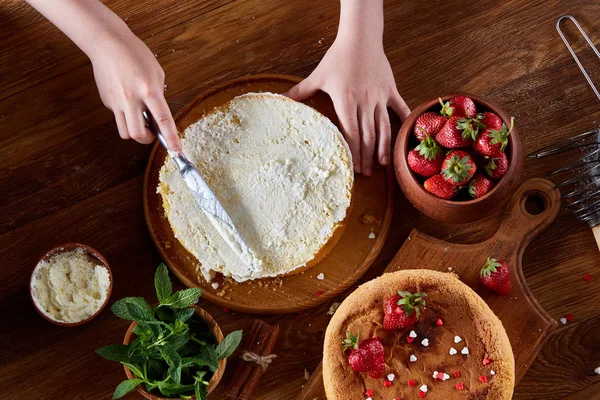 Kızlar el krem lezzetli çilekli pasta üstüne ekleme kapat, seçici odak, kapat.