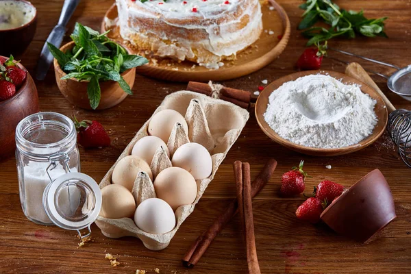 Çilekli tart ahşap arka plan üzerinde düz yatıyordu organik maddeler tarafından çevrili ekşi krem şanti ile kaplı.