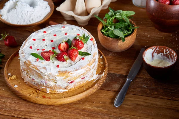Çilekli tart ahşap arka plan üzerinde düz yatıyordu organik maddeler tarafından çevrili ekşi krem şanti ile kaplı.