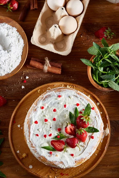 Çilekli tart ahşap arka plan üzerinde düz yatıyordu organik maddeler tarafından çevrili ekşi krem şanti ile kaplı.