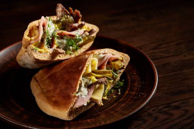 Et, peynir ve sos kil plaka ile doldurulmuş ahşap arka plan, yan görünüm, seçici odak üzerinde Pide.