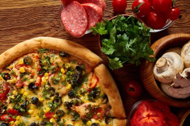 Pizza natürmort. Taze pişmiş pizza ve bileşenlerinin ahşap arka plan üzerine düzenlenmiş bir parçası.