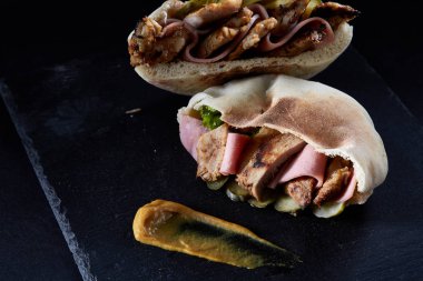 Siyah taşlı arka plan üzerinde Pide domuz eti, jambon, piccoli ve sos ile doldurulmuş.