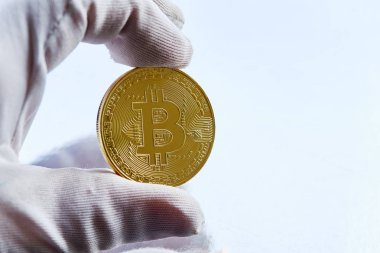 Bitcoin elinde, bitcoin, savaşı çek altın madeni para ile yumruk yumruğa, bokeh, beyaz, mavi, mor ışık arka plan üzerinde businees bitcoins adam el