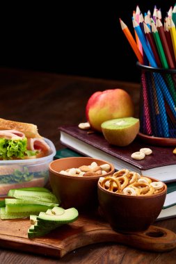 Okul öğle yemeği molası ile sağlıklı öğle yemeği kutusu ve okul malzemeleri ahşap masa, seçici odak kavramı.