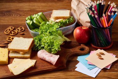 Okul öğle yemeği molası ile sağlıklı öğle yemeği kutusu ve okul malzemeleri ahşap masa, seçici odak kavramı.