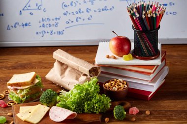 Okul öğle yemeği molası ile sağlıklı öğle yemeği kutusu ve okul malzemeleri ahşap masa, seçici odak kavramı.