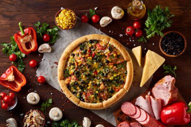 Pizza natürmort. Taze pişmiş pizza ve bileşenlerinin ahşap arka plan üzerine düzenlenmiş bir parçası.