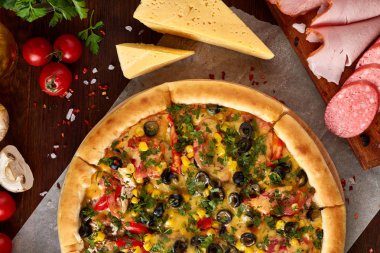 Pizza natürmort. Taze pişmiş pizza ve bileşenlerinin ahşap arka plan üzerine düzenlenmiş bir parçası.