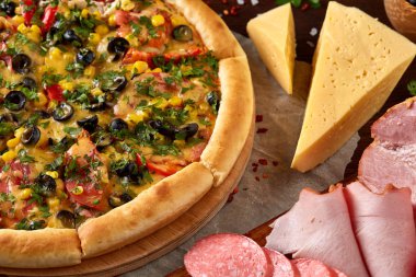 Pizza natürmort. Taze pişmiş pizza ve bileşenlerinin ahşap arka plan üzerine düzenlenmiş bir parçası.