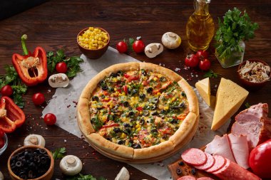 Pizza natürmort. Taze pişmiş pizza ve bileşenlerinin ahşap arka plan üzerine düzenlenmiş bir parçası.