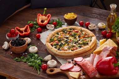 Pizza natürmort. Fırından yeni çıkmış pizza ve ahşap zemin üzerine düzenlenmiş bileşenleri.