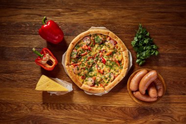 Pizza natürmort. Taze pişmiş pizza ve bileşenlerinin ahşap arka plan üzerine düzenlenmiş bir parçası.