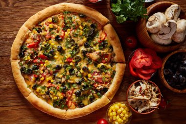 Pizza natürmort. Taze pişmiş pizza ve bileşenlerinin ahşap arka plan üzerine düzenlenmiş bir parçası.