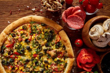 Pizza natürmort. Taze pişmiş pizza ve bileşenlerinin ahşap arka plan üzerine düzenlenmiş bir parçası.