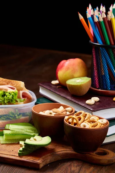 Okul öğle yemeği molası ile sağlıklı öğle yemeği kutusu ve okul malzemeleri ahşap masa, seçici odak kavramı.