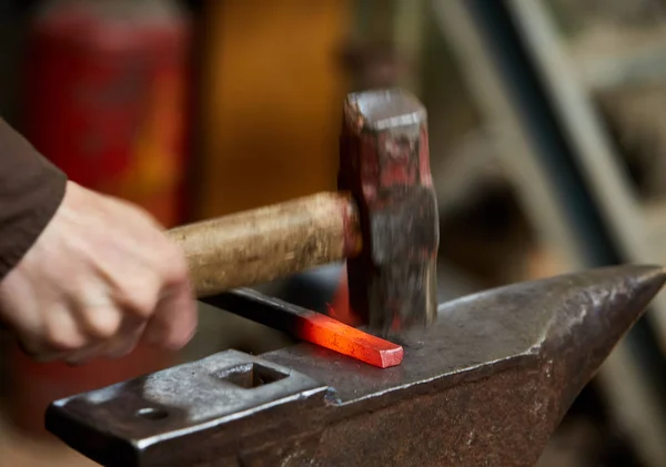 Primer plano de un herrero manos manipulando una pieza de metal por encima de su forja, enfoque selectivo . — Foto de Stock