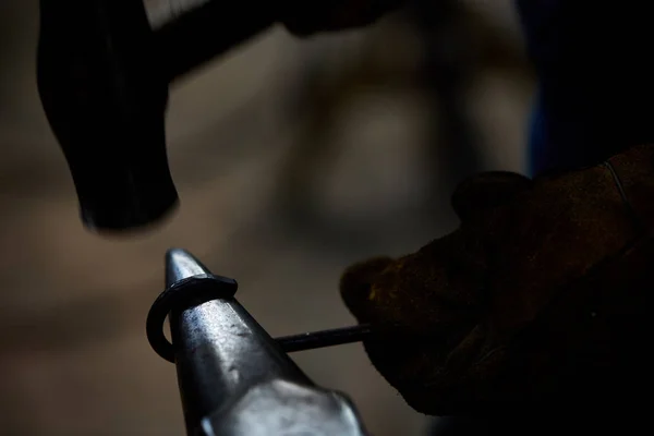 Close-up van een smeden handen manipuleren van een metalen stuk boven zijn smederij, selectieve aandacht. — Stockfoto