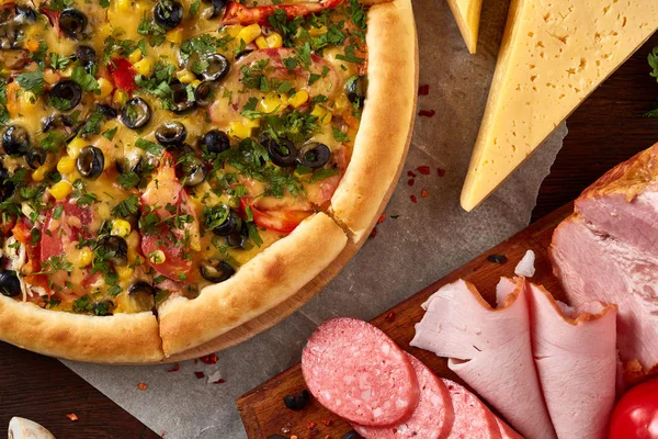 Pizza natürmort. Taze pişmiş pizza ve bileşenlerinin ahşap arka plan üzerine düzenlenmiş bir parçası.