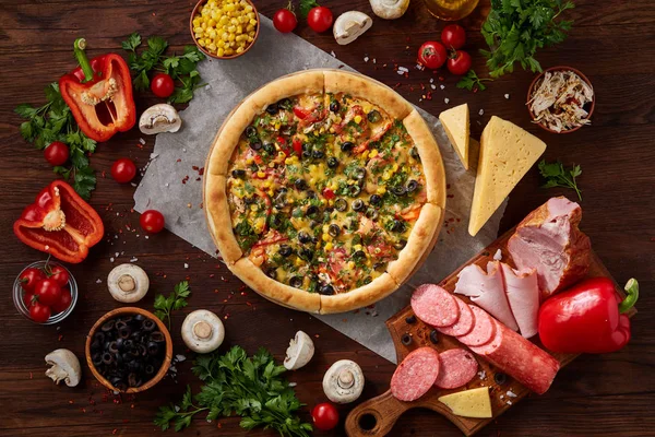 Pizza natürmort. Taze pişmiş pizza ve bileşenlerinin ahşap arka plan üzerine düzenlenmiş bir parçası.