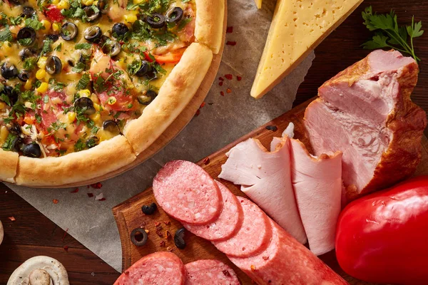 Pizza natürmort. Taze pişmiş pizza ve bileşenlerinin ahşap arka plan üzerine düzenlenmiş bir parçası.